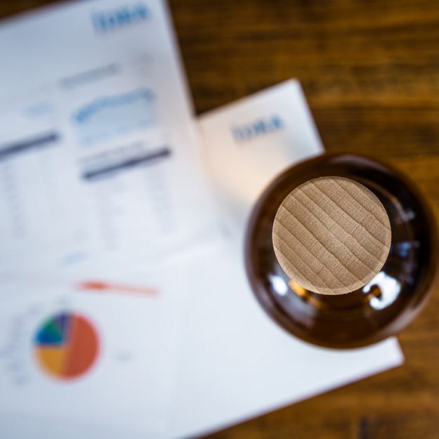 Blick von oben auf eine Whiskyflasche und Unterlagen: Marktforschung bei den Idea Distillers.