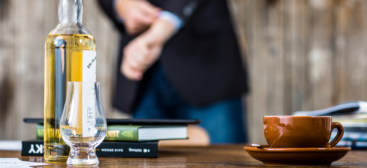 Whisky und Kaffeetasse auf einem Holztisch: Die Idea Distillers treten für maßvollen Genuss ein.