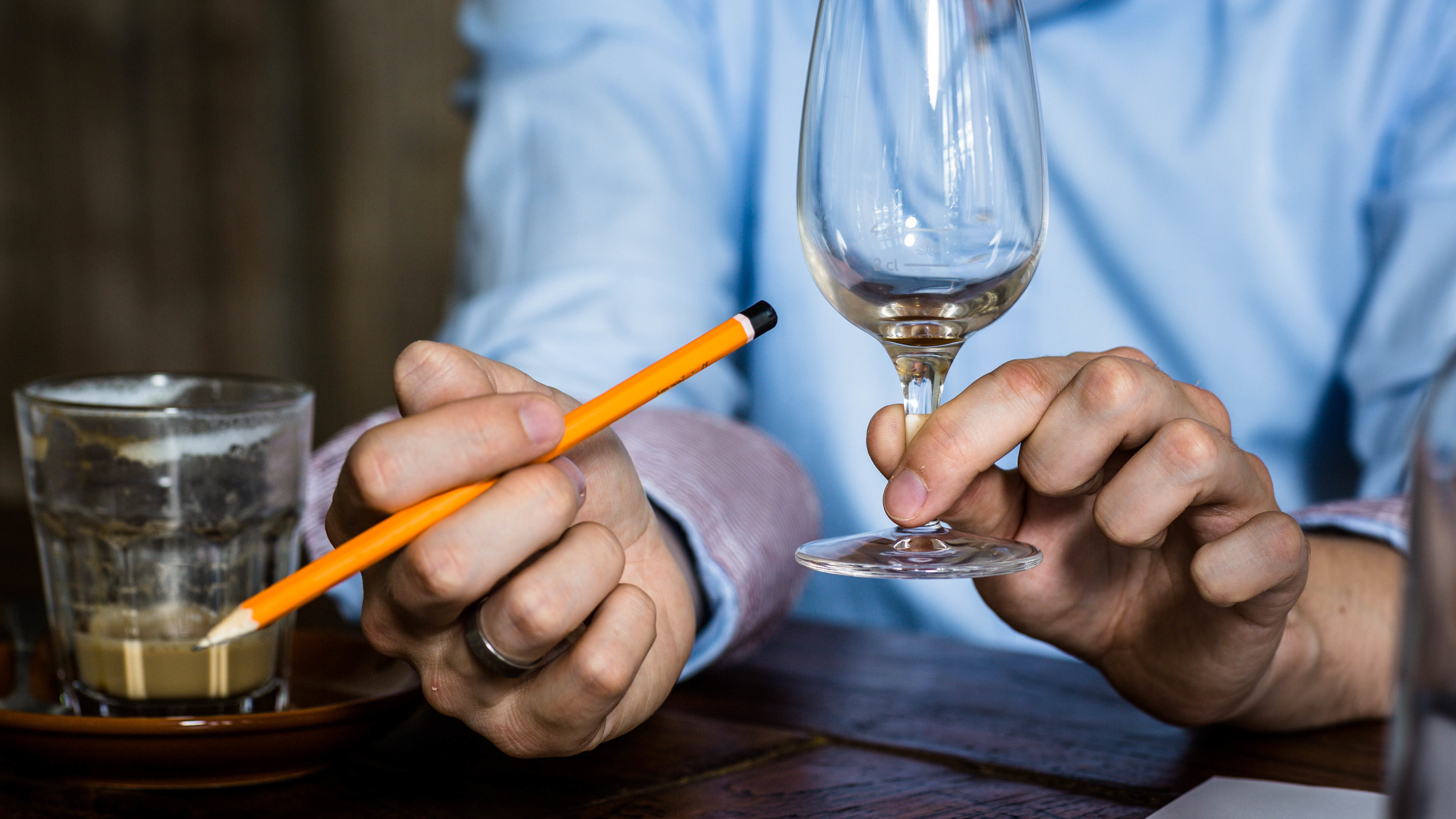 Spirituosen-Wettbewerber_Idea-Distillers Spirituosen-Wettbewerbe: Hand hält Whiskyglas und Bleistift (Foto)