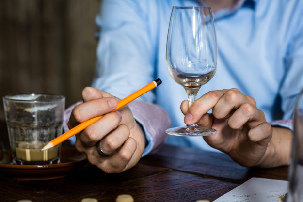 Spirituosen-Wettbewerbe: Hand hält Whiskyglas und Bleistift (Foto)