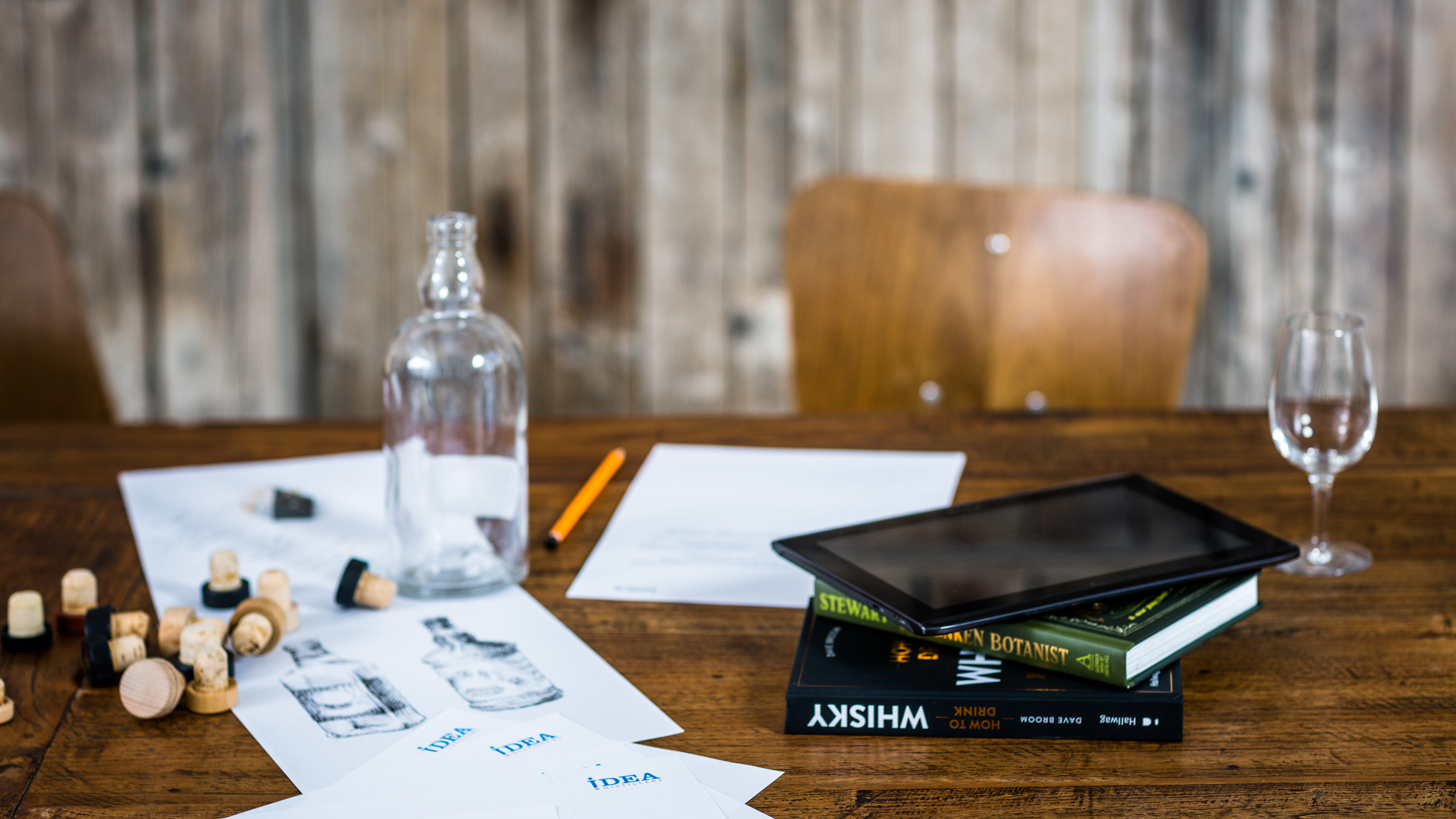 Einstieg in die Direktvermarktung: Glasflasche, Glas, Korken, Notizen, Bücher und ein Tablett auf einem Holztisch (Foto)