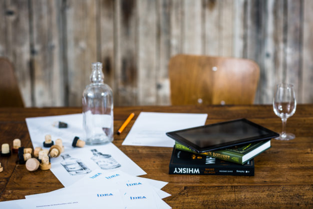 Einstieg in die Direktvermarktung: Glasflasche, Glas, Korken, Notizen, Bücher und ein Tablett auf einem Holztisch (Foto)